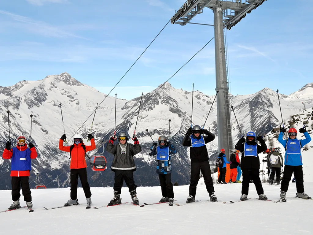 Gruppe jubelt mit erhobenen Armen unter der Seilbahn.